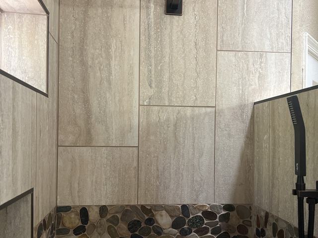 Wood look tile shower with river rock band